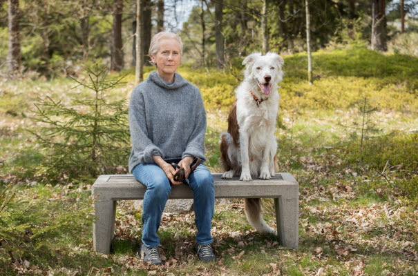 ALMA laureate Eva Lindström and her dog sitting at a bench in the wood.