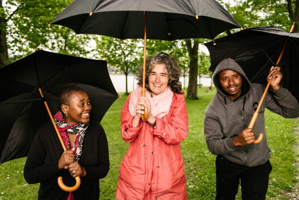 Three people from PRAESA with umbrellas on a rainy day in Stockholm