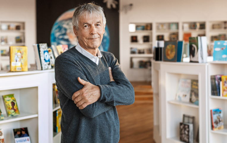 A grey haired man leaning against a wall