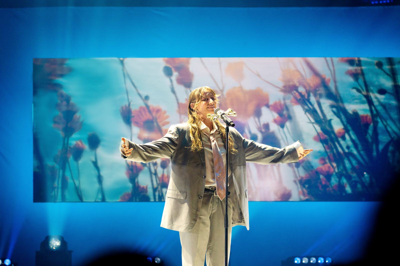 Silvana Imam on stage in front of a LED screen with flowers